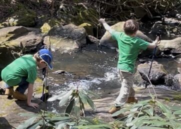 Two young boys play by a creek
