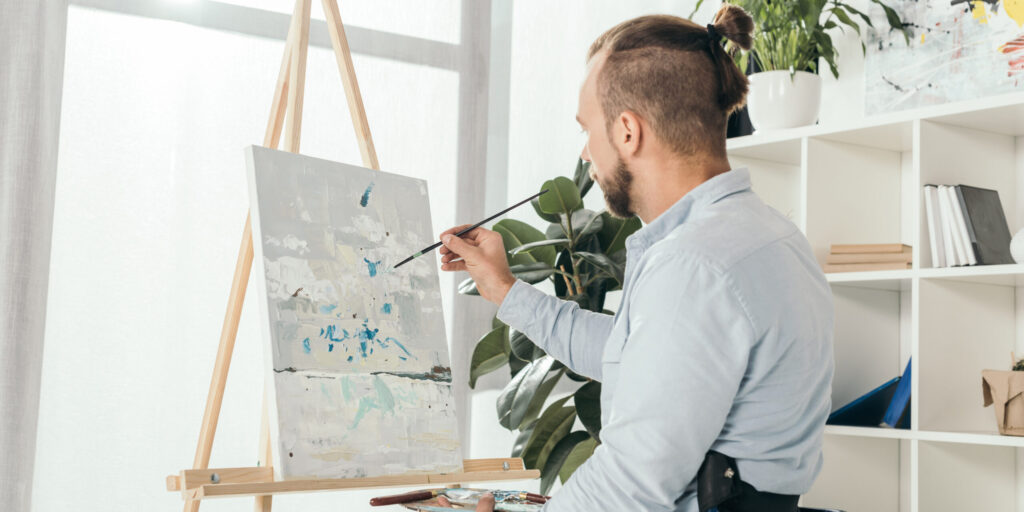 disabled man on wheelchair painting in front of window at home
