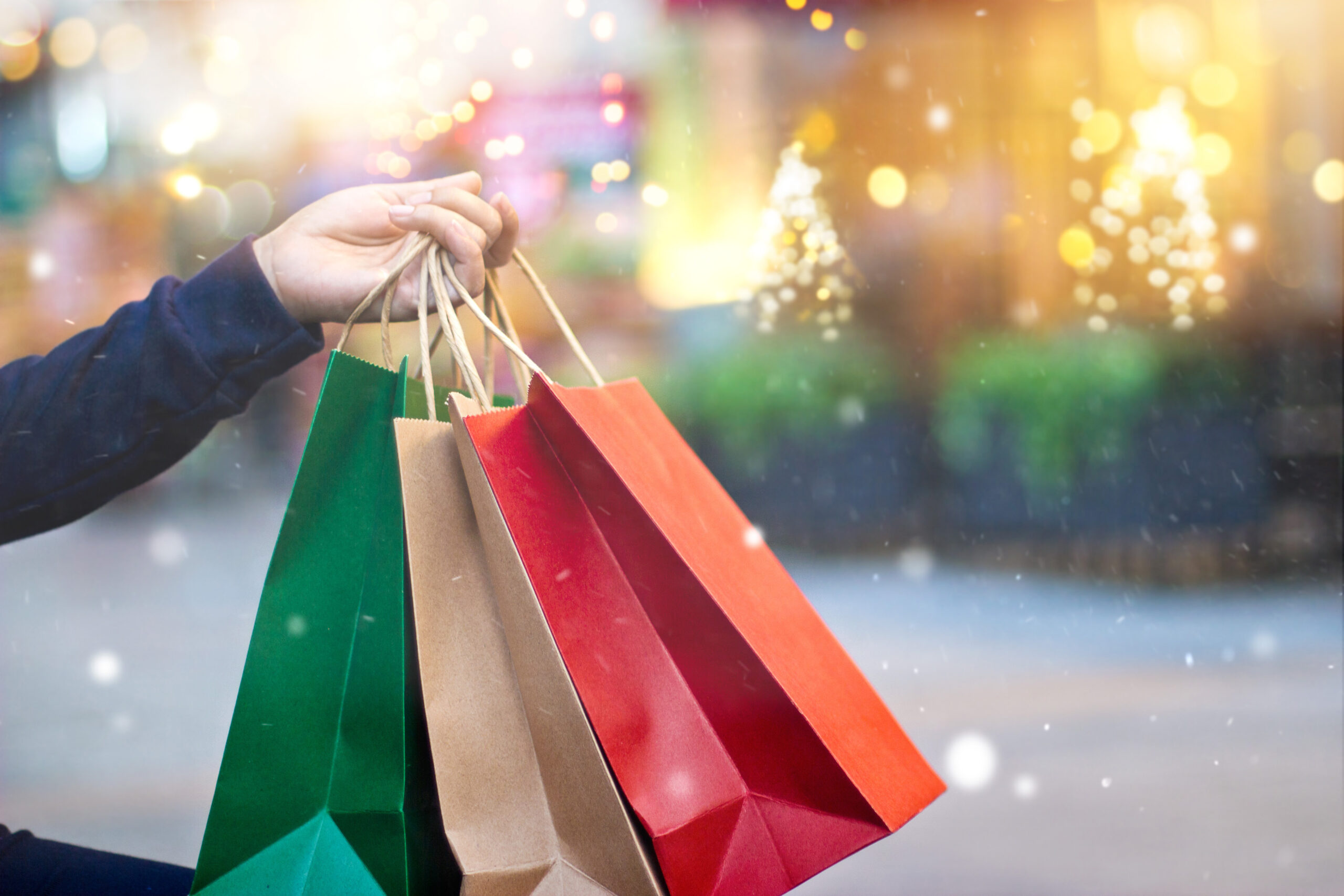 Christmas shopping - shopping bags in hand with snowflake on Christmas decoration and lighting on street background